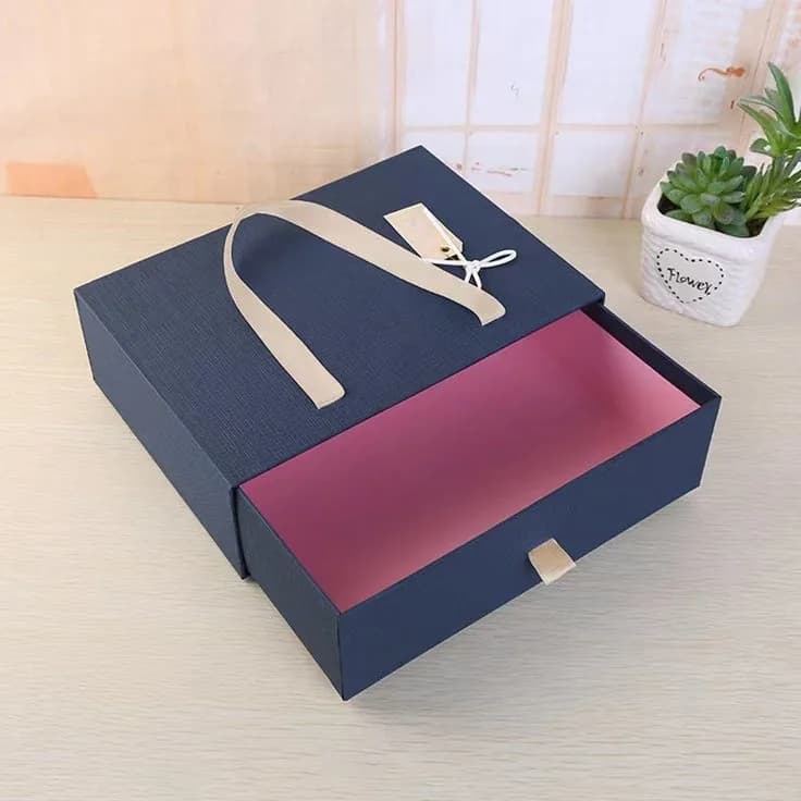 A navy sleeve box slid part way open to show the tray and its contrasting lining