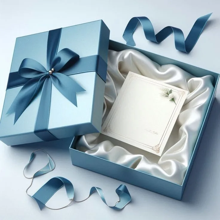 A blue rigid box with its lid off, lined with white satin and holding a printed card