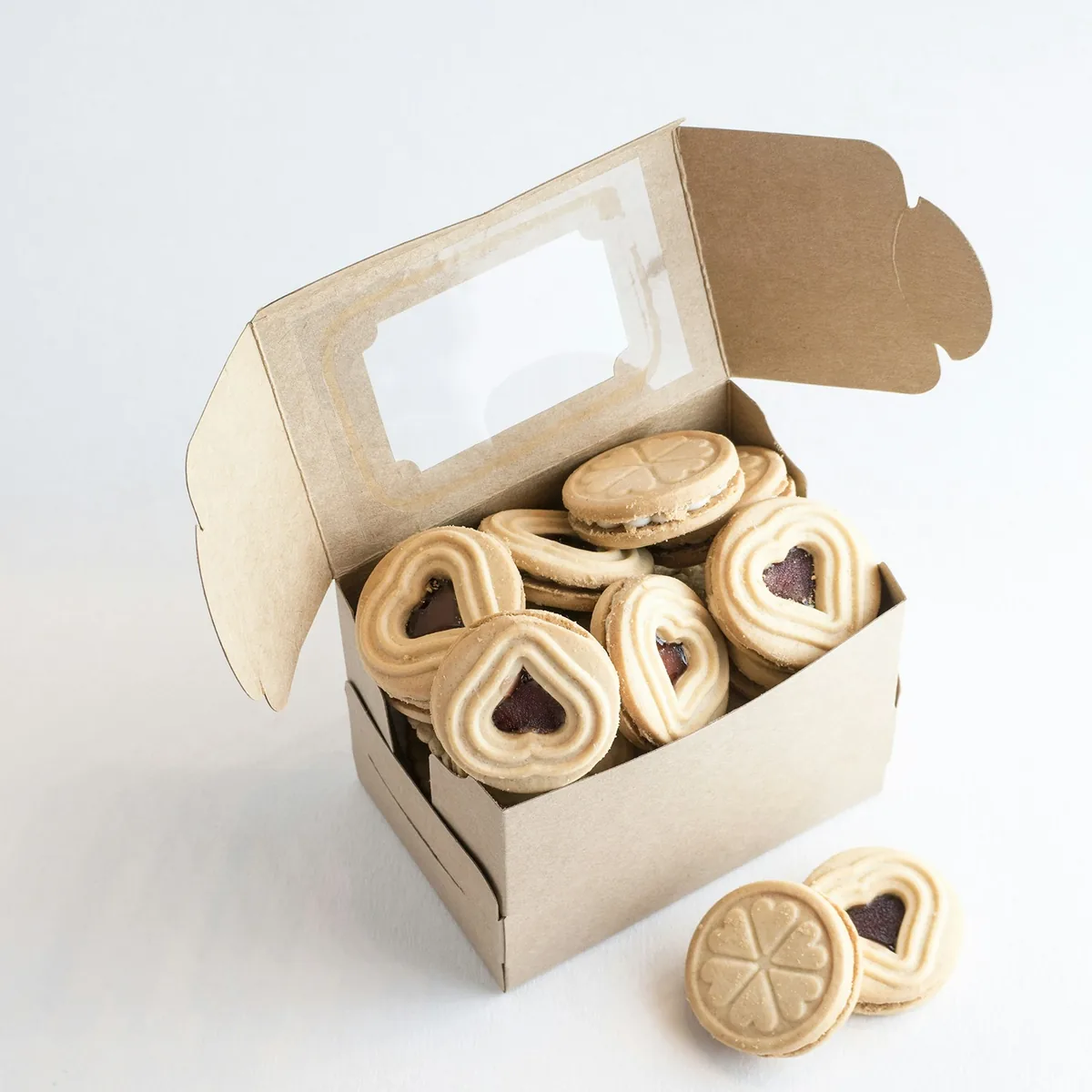 A kraft box with a clear film window in its lid, open, filled with shortbread biscuits