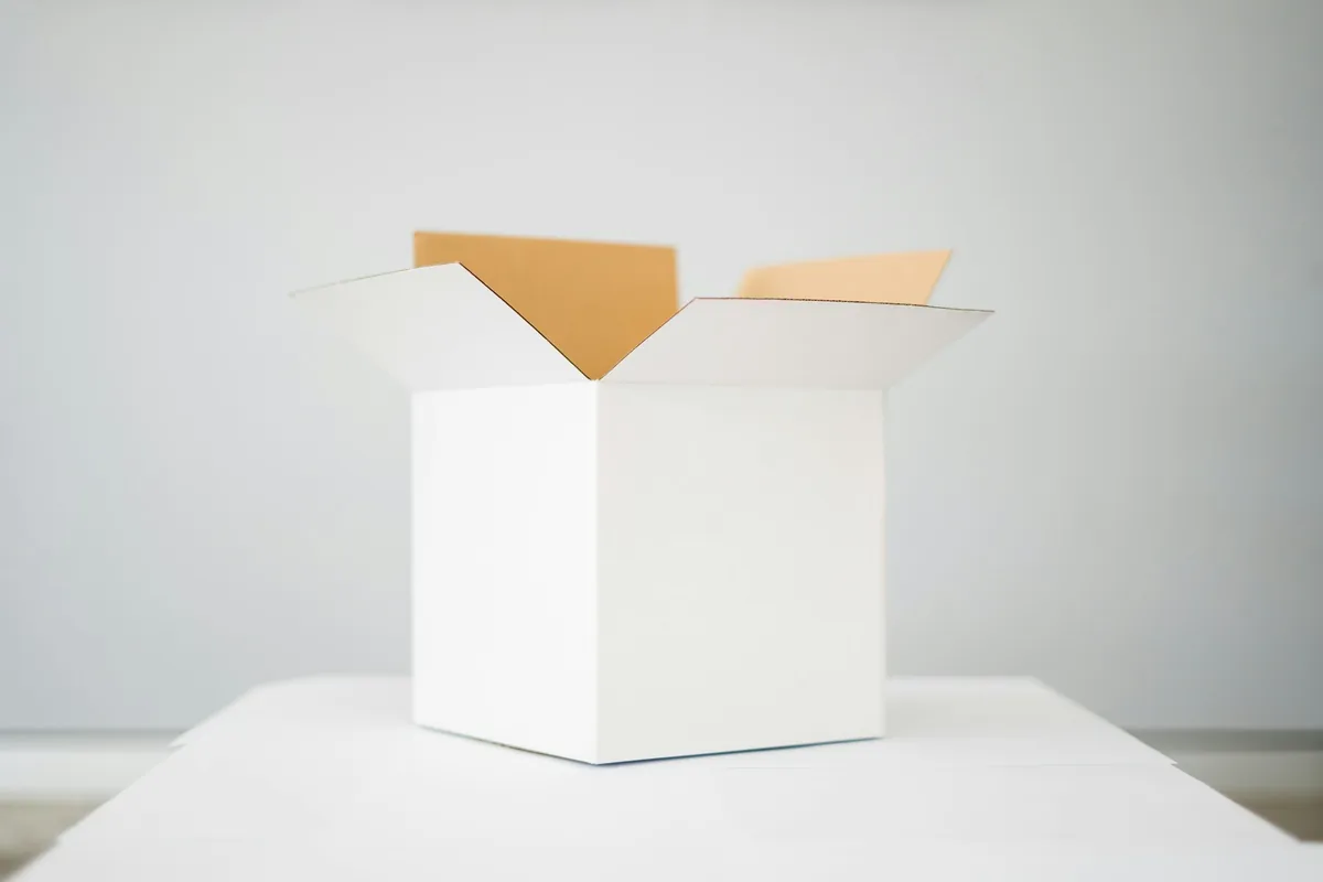 A white corrugated shipping carton with its top flaps open, showing the kraft inner liner